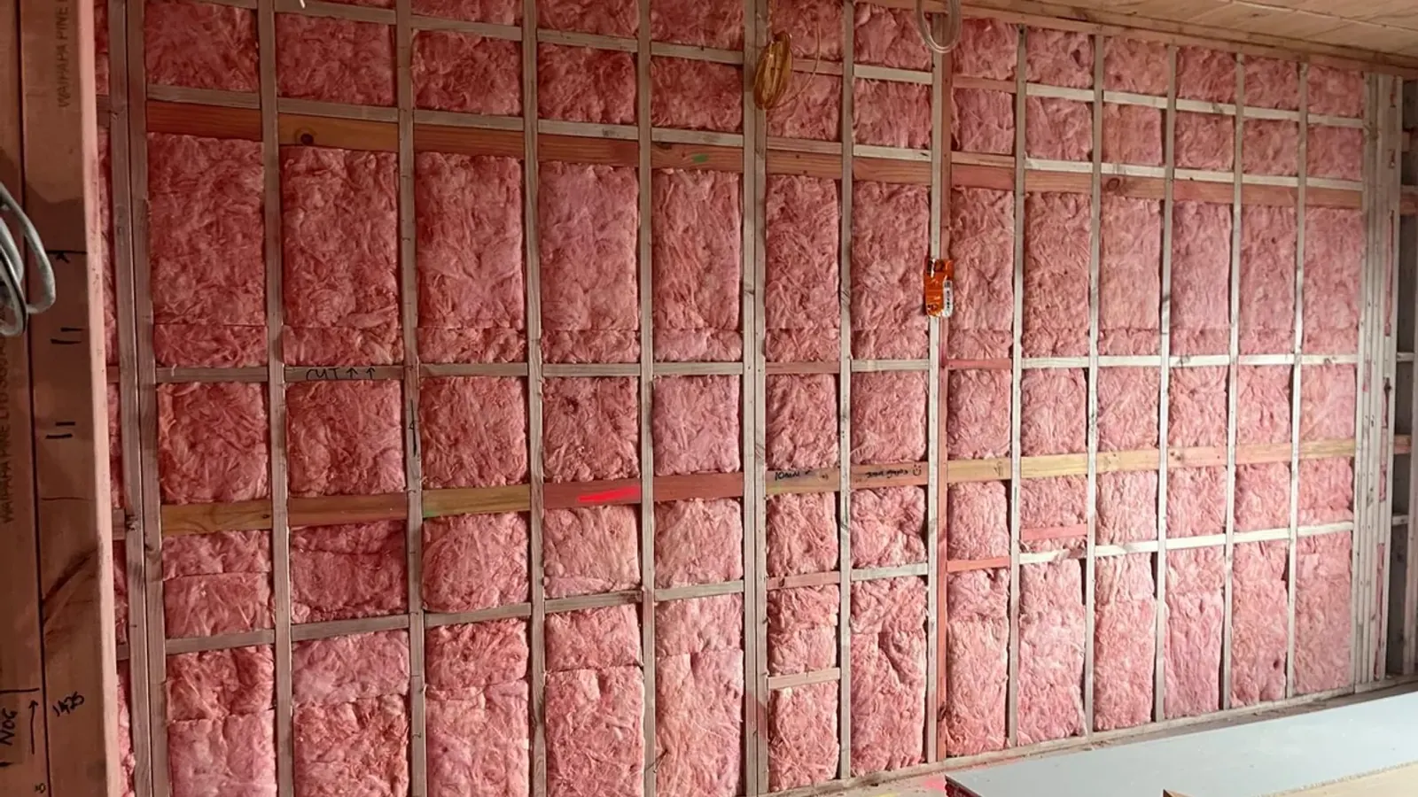 Pink Batts thermal insulation packed between timber studs on an Auckland commercial fitout — R-Value Insulation Co install.